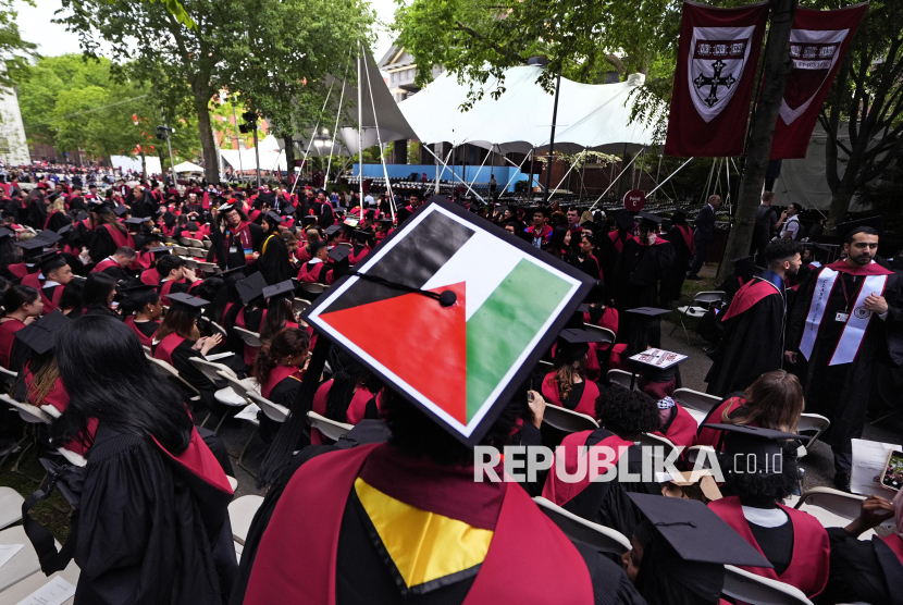 Seorang mahasiswa mengibarkan bendera Palestina di papan mortirnya saat para wisudawan duduk di Harvard Yard saat wisuda di Universitas Harvard, Kamis, 23 Mei 2024, di Cambridge, AS.