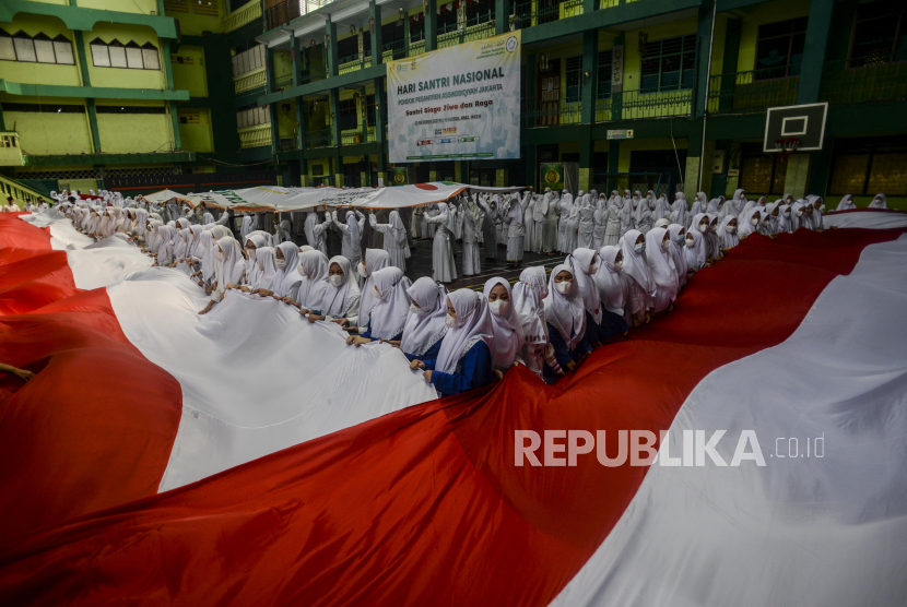 Sejumlah santri saat membentangkan bendera Merah Putih di Pondok Pesantren Asshiddiqiyah, Kebon Jeruk, Jakarta, Jumat (22/10). Bendera Merah Putih sepanjang 200 meter tersebut dibentangkan mengelilingi lapangan Pondok Pesantren Asshiddiqiyah dalam rangka memeriahkan Hari Santri Nasional 2021 yang bertemakan Santri Siaga Jiwa dan Raga. Republika/Putra M. Akbar
