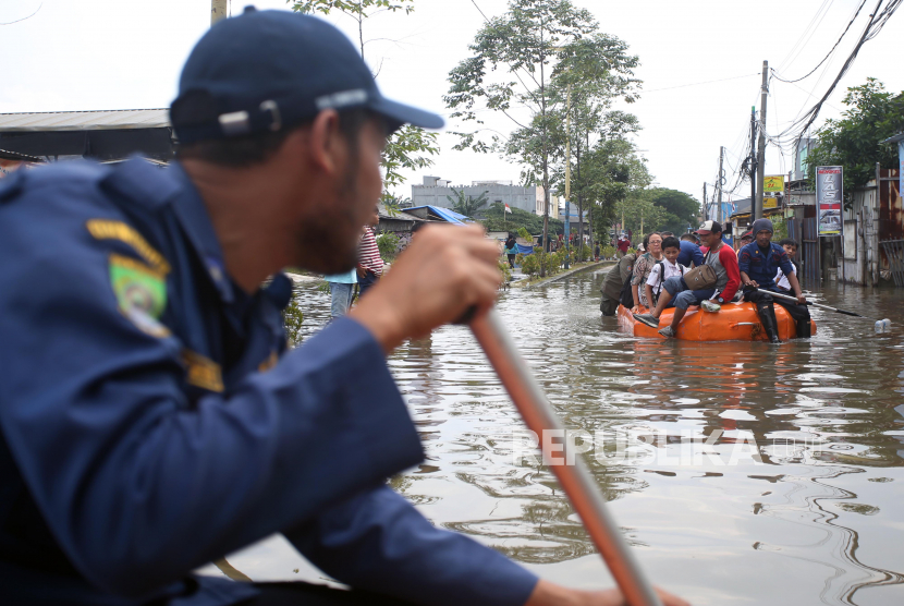 Petugas damkar dengan menggunakan perahu karet mengevakuasi warga yang terdampak banjir.