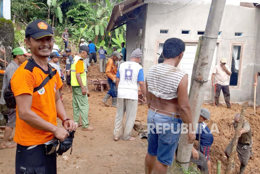 Petugas dibantu warga berupaya membersihkan material longsor di Desa Cikalong, Kecamatan Sodonghilir, Kabupaten Tasikmalaya, Kamis (11/1/2024). 