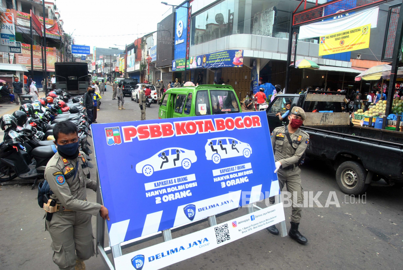 Anggota Satpol PP Kota Bogor membawa papan informasi dalam razia operasi kepatuhan Pembatasan Sosial Berskala Besar (PSBB) 