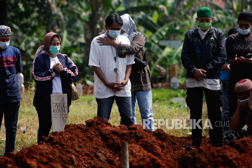  Kerabat seseorang yang meninggal dengan COVID-19 berdoa di atas kuburan mereka saat pemakaman di sebuah pemakaman di Depok, Indonesia, 27 Juni 2021. 