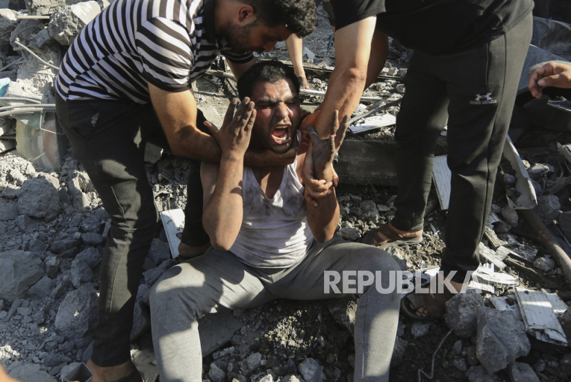 Warga Palestina menghibur pria yang menangis kehilangan kerabatnya di bawah reruntuhan rumah. Di KTT OKI, Presiden Jokowi menegaskan agar kekejaman Israel untuk segera dihentikan.