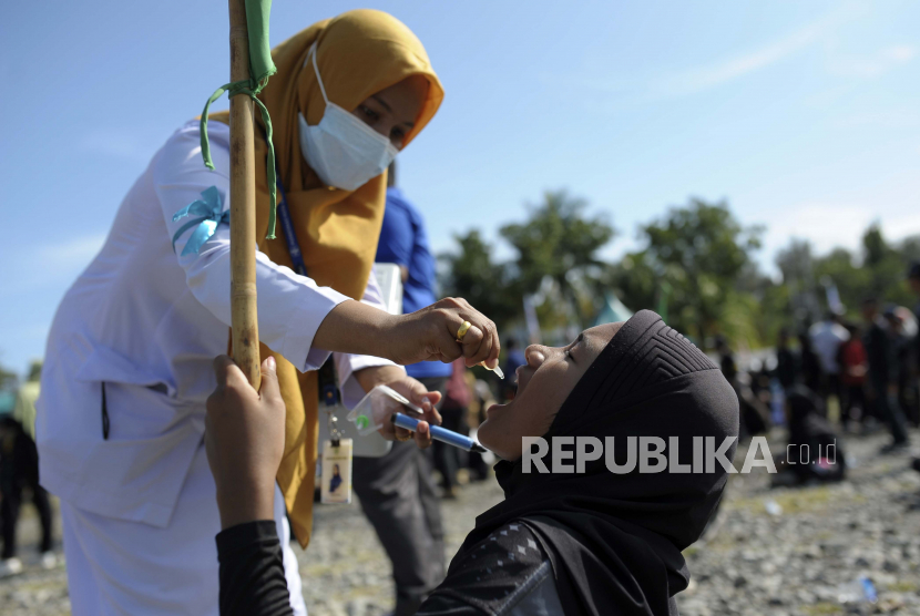 Seorang pekerja medis memberikan vaksin kepada seorang anak perempuan selama kampanye imunisasi polio di Sigli Town Square di Pidie, provinsi Aceh, Indonesia, Senin, 28 November 2022. Indonesia telah memulai kampanye melawan virus polio di provinsi konservatif negara itu setelah beberapa anak ditemukan terinfeksi penyakit yang sangat menular yang dinyatakan diberantas di negara itu kurang dari satu dekade lalu.