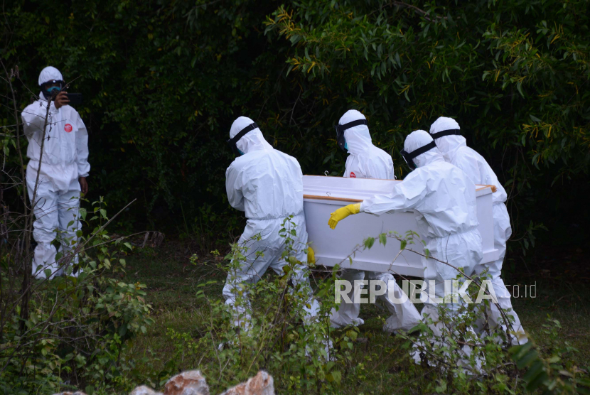 Petugas medis yang mengenakan APD lengkap mengangkat peti berisi jenazah pasien positif Covid-19 menuju lokasi pemakaman di Kabupaten Aceh Besar, Aceh, Kamis (16/7/2020). Pada pekan ini terjadi dua kali pengambilan jenazah secara paksa oleh warga dan tidak dimakamkan dengan protokol Covid-19. (ilustrasi)