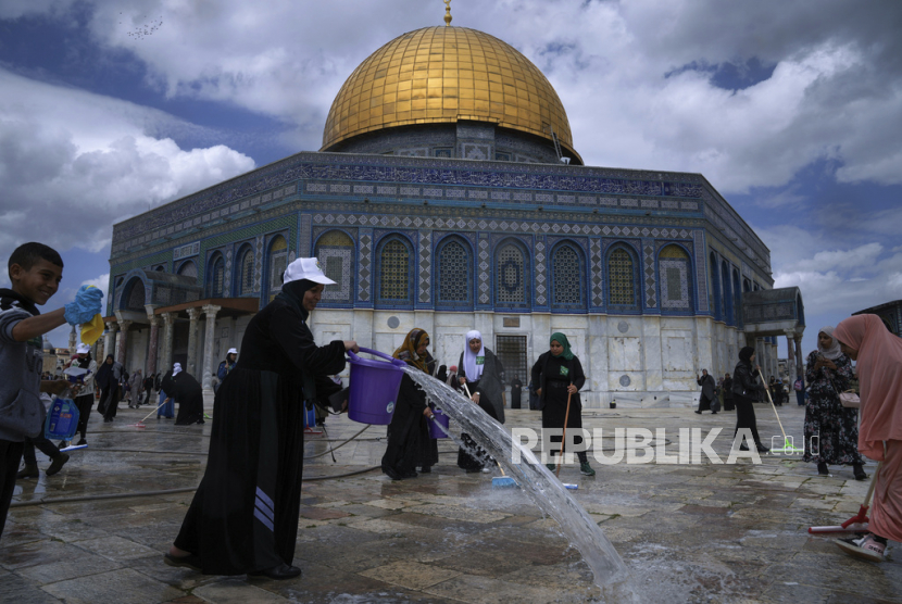 Relawan Palestina membersihkan tanah di luar Masjid Dome of Rock di kompleks Masjid Al-Aqsa.