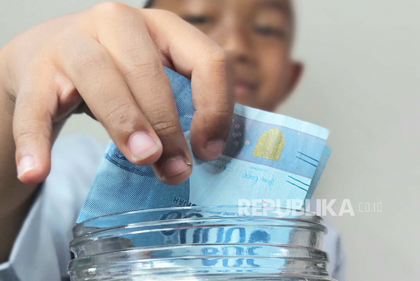 Anak menabungkan uang yang didapatnya sebagai tunjangan hari raya (THR). (Ilustrasi)