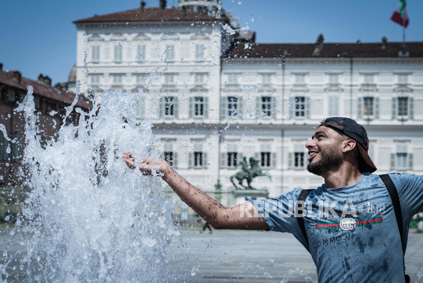 Seorang pria mendinginkan diri di air mancur Piazza Castello di tengah suhu tinggi di Turin, Italia. Tahun ini akan menjadi tahun terpanas yang pernah tercatat.
