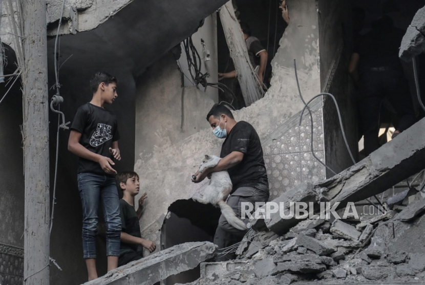 Warga Palestina mencari mayat dan korban di reruntuhan bangunan tempat tinggal yang rata akibat serangan udara Israel, di kamp pengungsi Khan Younis di Jalur Gaza selatan,  Kamis (19/10/2023). 
