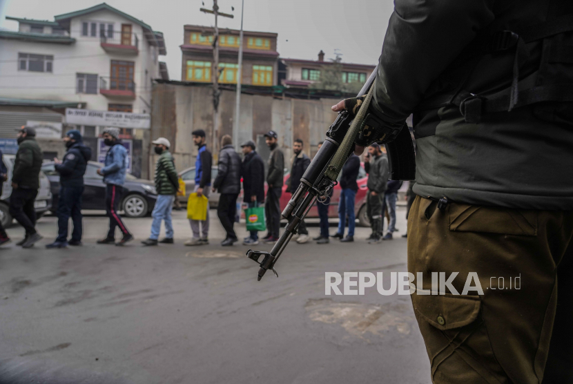 Seorang polisi India menjaga para pria Kashmir berdiri dalam antrian selama pemeriksaan keamanan. ilustrasi
