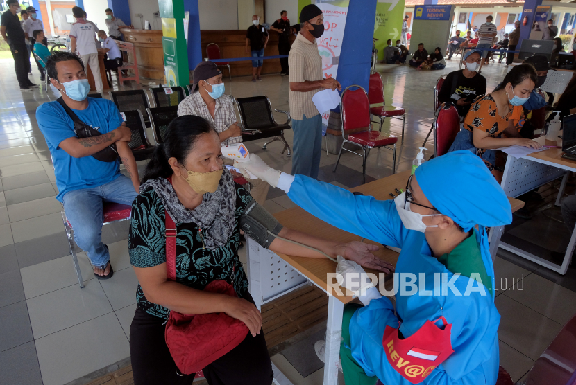 Petugas kesehatan memeriksa suhu tubuh seorang penumpang bus dalam Gerai Vaksin Presisi Bhakti Kesehatan Bhayangkara Untuk Negeri di Terminal Tipe A Mengwi, Badung, Bali, Jumat (9/7/2021). Kegiatan vaksinasi COVID-19 yang digelar selama pelaksanaan Pemberlakuan Pembatasan Kegiatan Masyarakat (PPKM) Darurat tersebut menyasar Pelaku Perjalanan Dalam Negeri (PPDN) dengan jumlah kuota 150 orang per hari itu bertujuan mendukung percepatan penanganan COVID-19 untuk masyarakat sehat dan pemulihan ekonomi nasional menuju Indonesia maju. 