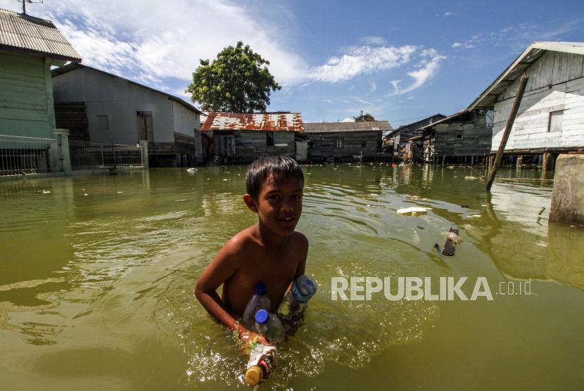 Seorang anak mengumpulkan botol bekas saat banjir pasang air laut atau rob (ilustrasi)