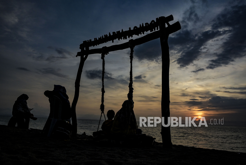 Sejumlah pengunjung menikmati suasana matahari terbenam (sunset) akhir tahun 2023 di kawasan pantai, Senggigi, Lombok Barat, NTB, Ahad (31/12/2023). Menikmati sunset akhir tahun di pinggir pantai menjadi alternatif sebagian warga untuk melewati pergantian tahun di Lombok. 