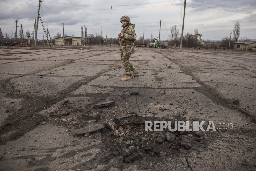 Seorang tentara Ukraina melihat sebuah lubang dari peluru yang ditembakkan oleh separatis pro-Rusia di desa Novoluhanske, wilayah Luhansk, Ukraina, Sabtu, 19 Februari 2022. Pemerintah China mendorong solusi diplomatik untuk menyelesaikan krisis Rusia-Ukraina. 