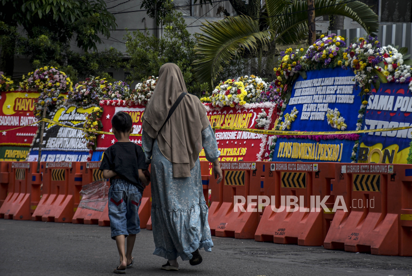 Warga berjalan di depan deretan karangan bunga pascaledakan bom bunuh diri di Mapolsek Astana Anyar, Jalan Astana Anyar, Kota Bandung, Jumat (9/12/2022). Polisi memulihkan trauma warga sekitar Polsek Astanaanyar setelah adanya bom.