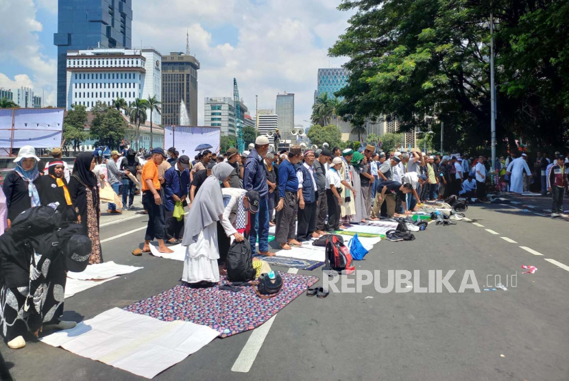 Massa aksi melaksanakan sholat zuhur berjamaah di kawasan Patung Kuda, Jalan Medan Merdeka Barat, Gambir, Jakarta Pusat, Senin (22/4/2024). 