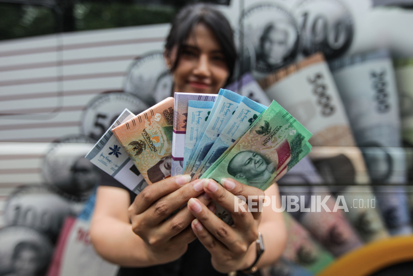 Warga memperlihatkan uang pecahan baru saat berlangsung layanan penukaran uang.