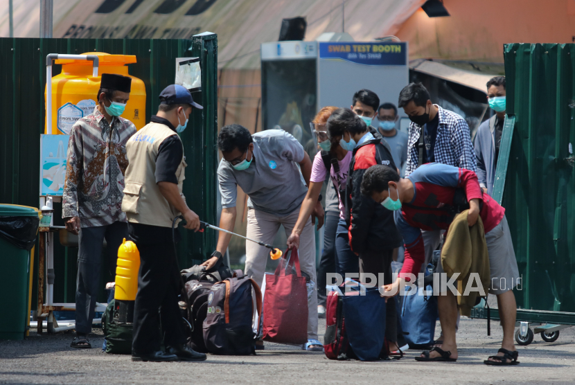 Petugas menyemprotkan larutan disinfektan ke barang bawaan pasien Covid-19 yang telah sembuh di Rumah Sakit Lapangan Kogabwilhan II Jalan Indrapura, Surabaya, Jawa Timur, Ahad (14/3).