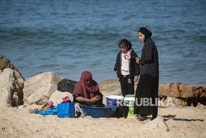 Anggota keluarga Palestina mencuci pakaian di pantai dekat kamp pengungsi Rafah, Jalur Gaza selatan, (11/2/2024).
