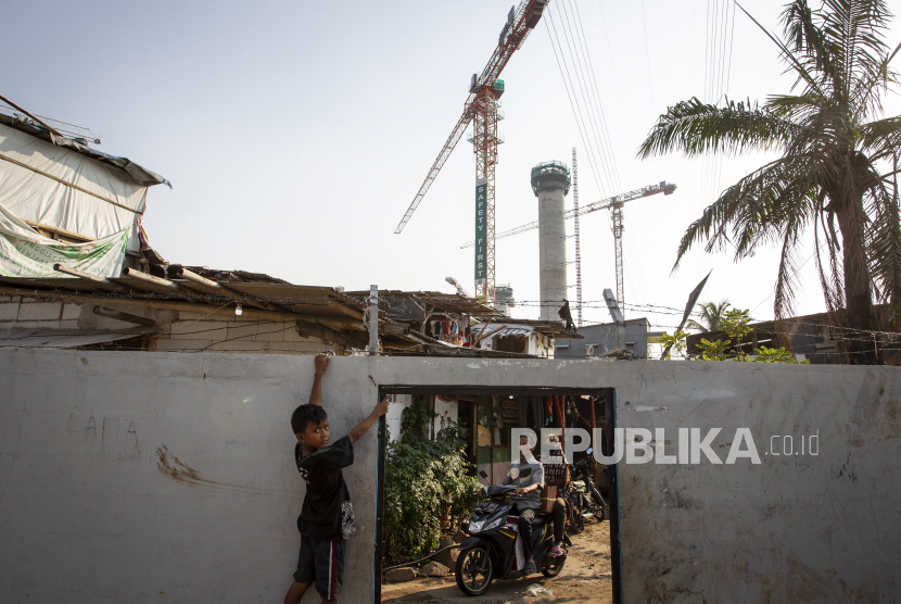 [Ilustrasi] Warga Kampung Bayam beraktivitas dengan latar belakang proyek pembangunan Jakarta International Stadium (JIS).