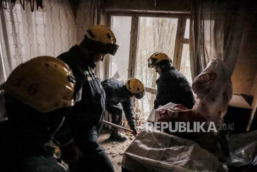 Pekerja layanan darurat membersihkan puing-puing dari blok apartemen yang rusak akibat serangan roket di Kyiv (Kiev), Ukraina, (23/1/2024). 