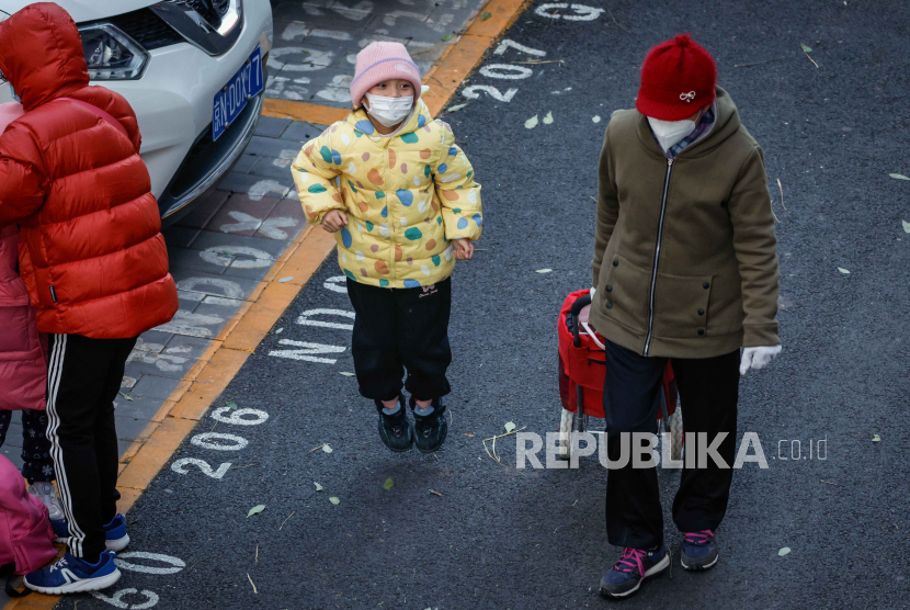 Seorang anak memakai masker setelah keluar dari sekolah di Beijing, Cina, 23 November 2023.