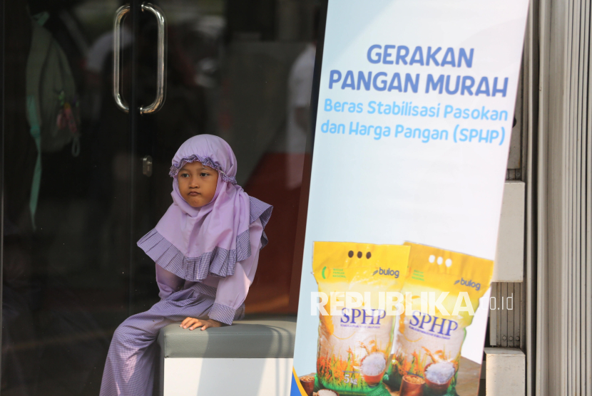 Seorang anak menunggu orang tuanya membeli beras program Stabilisasi Pasokan dan Harga Pangan (SPHP) saat kegiatan Gerakan Pangan Murah di Kantor Pos Fatmawati, Jakarta, Jumat (18/7/2025). Pemerintah mulai menyalurkan beras SPHP sebanyak 1,3 juta ton untuk meredam gejolak kenaikan harga pangan di tengah masyarakat. Pendistribusian sebanyak 1,3 juta ton beras SPHP tersebut dilakukan selama periode Juli hingga Desember 2025. Untuk harga beras SPHP tersebut dibanderol dengan harga Rp62.500 untuk kemasan 5 kg, Warga yang datang hanya boleh membeli maksimal 10 kg atau 2 kemasan beras SPHP per transaksi.
