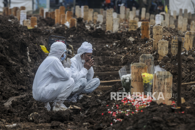 Sejumlah keluarga dan kerabat jenazah pasien Covid-19 berdoa di TPU Srengseng Sawah Dua, Jagakarsa, Jakarta Selatan, Kamis (25/2).