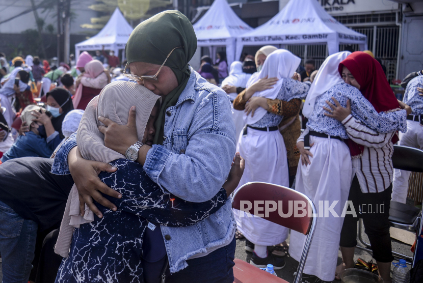 Anak-anak dicium oleh ibunya saat aksi cuci kaki ibu di Jalan Suryapranoto, Gambir, Jakarta, Ahad (18/12/2022). 