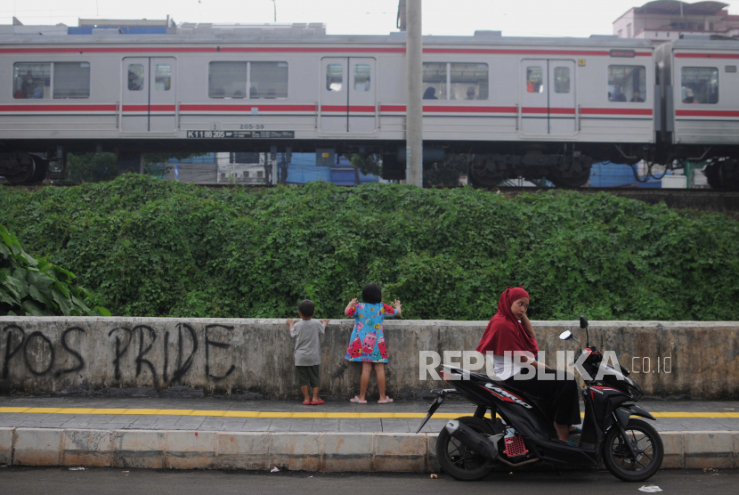 Anak-anak melihat kereta melintas di jalan tembusan Pasar Minggu menuju Jalan Raya Tanjung Barat di Jakarta Selatan, Senin (22/5/2023).
