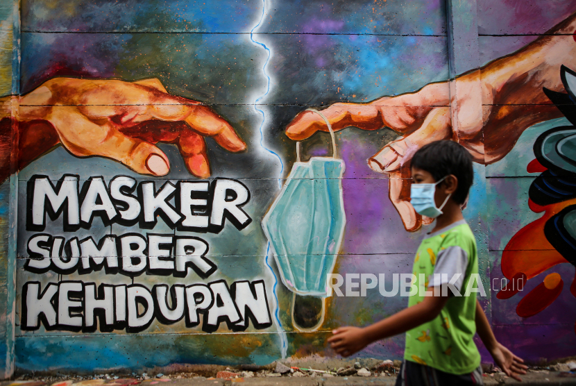 Seorang bocah melintas di depan mural tentang penggunaan masker di Kota Tangerang, Banten, Minggu (21/12/2020). Mural tersebut dibuat sebagai edukasi kepada masyarakat untuk selalu menggunakan masker guna mencegah penyebaran Covid-19. 