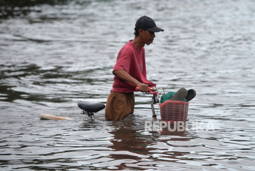 Warga menerobos banjir di Kawasan Kaligawe, Semarang, Jawa Tengah, Senin (2/1/2023). Tingginya curah hujan di Semarang menyebabkan ruas jalan raya Semarang-Demak terganggu. Saat ini hanya bisa dilewati oleh kendaraan besar.