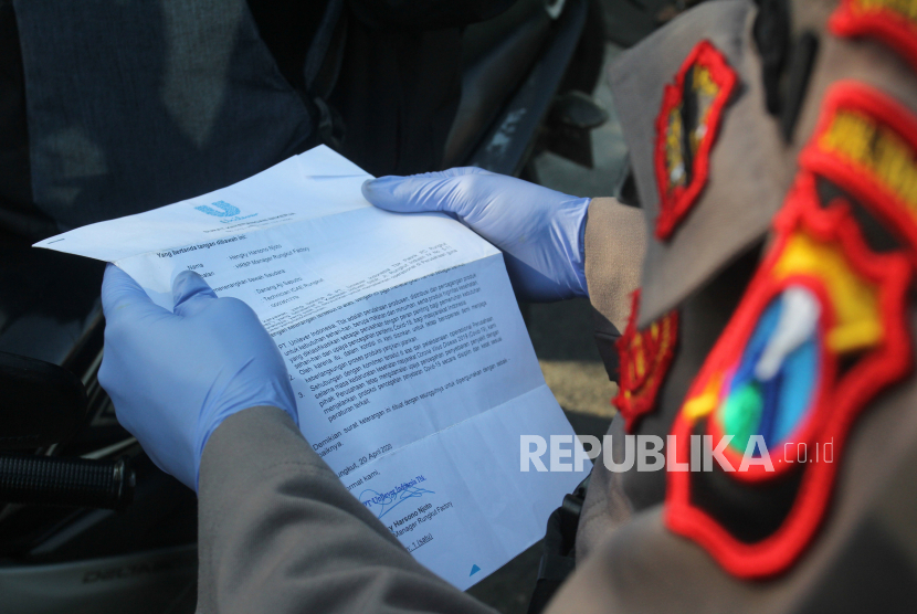 Polisi memeriksa dokumen perjalanan warga saat melakukan penyekatan Pembatasan Sosial Berskala Besar (PSBB) di Bundaran Waru, Surabaya, Jawa Timur. (ilustrasi)