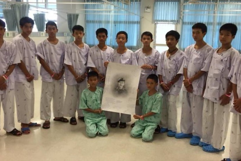 12 anak yang tergabung dalam tim sepak bola 'Wild Boars' berduka atas kematian salah seorang penyelam yang menyelamatkan mereka, Saman Kunan (dalam lukisan)