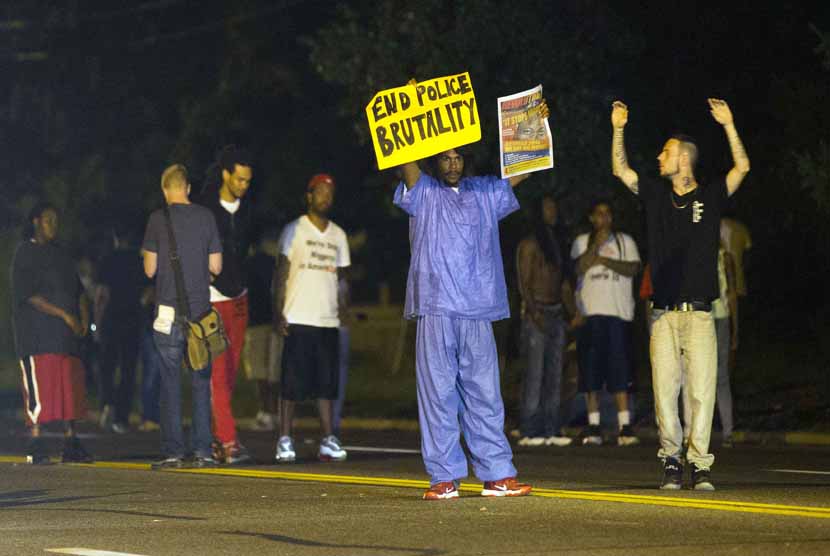  Massa berkumpul memprotes aksi kekerasan yang dilakukan polisi dan menyebabkan tewasnya seorang remaja kulit hitam berusia 18 tahun di Ferguson, Missouri, Senin (11/8).    (REUTERS/Mario Anzuoni)