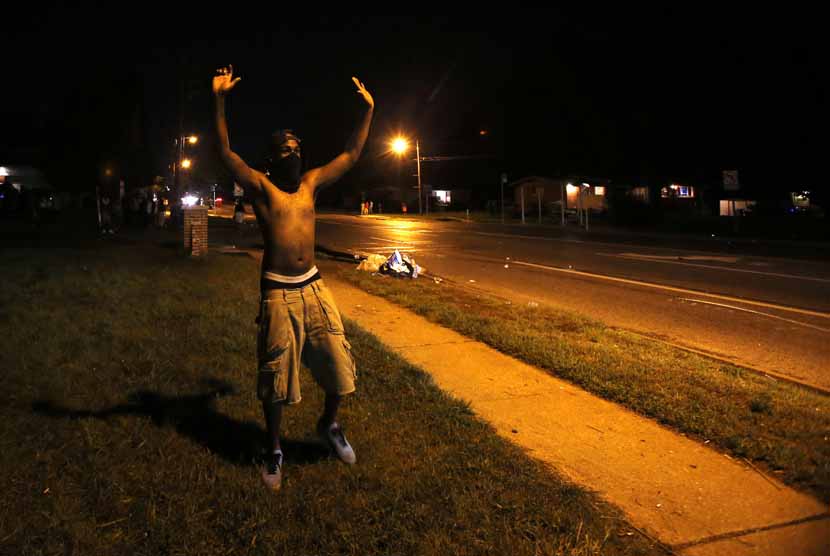  Seorang pengunjuk rasa mengangkat tangannya di Ferguson, Missouri, Senin (11/8).    (REUTERS/Mario Anzuoni)