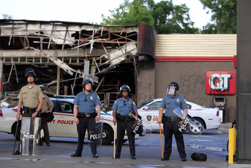  Pasukan polisi berjaga di depan bangunan super market yang dibakar massa di Ferguson, Missouri, Senin (11/8).    (AP/Jeff Roberson)