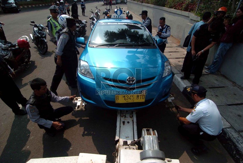 Officers tow an illegally parked taxis in Kalibata, South Jakarta on Monday. 