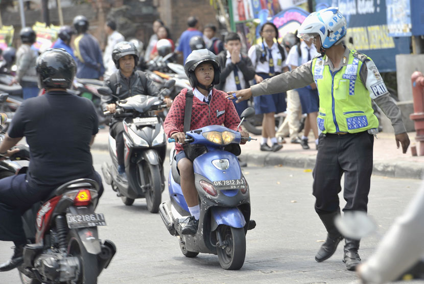  Seorang polisi menghentikan pelajar bersepeda motor.