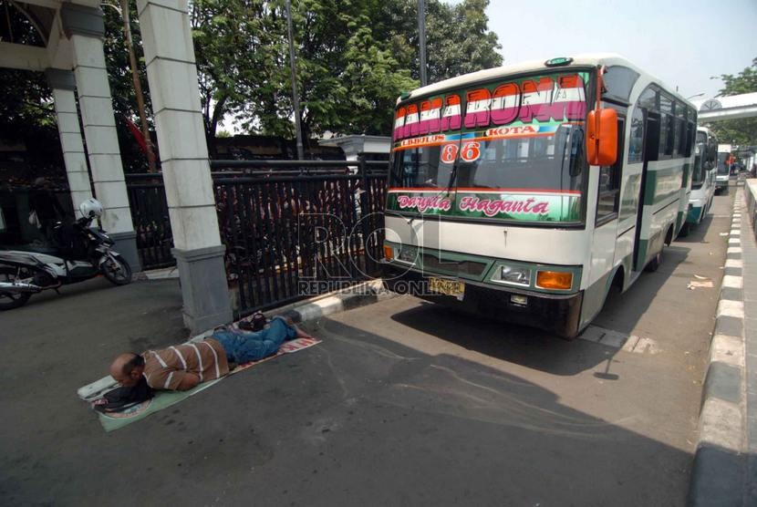  Seorang supir bus tidur terlelap di depan busnya di Terminal Bus Kota Tua, Jakarta Barat, Selasa (9/9).   (Republika/Raisan Al Farisi)