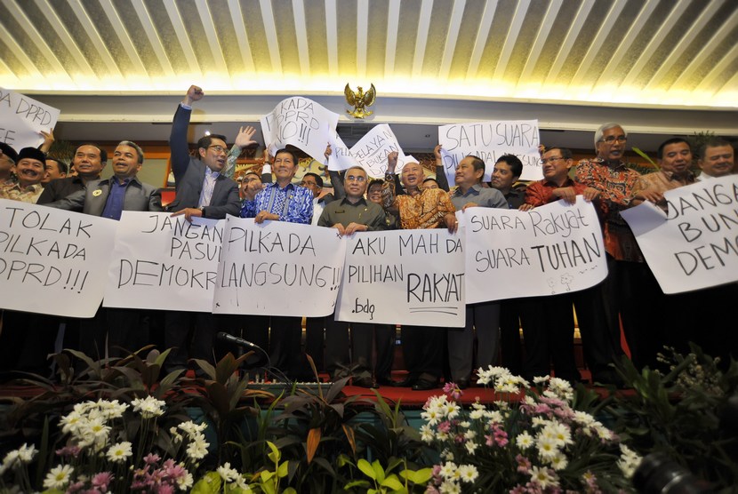  Ketua Apkasi Isran Noor (tengah) dan Ketua Apeksi Vicky Lumentut (kelima kiri) bersama perwakilan bupati-walikota menggelar poster saat rapat membahas polemik RUU Pemilihan Kepala Daerah, di Jakarta, Kamis (11/9). (Antara/Yudhi Mahatma)