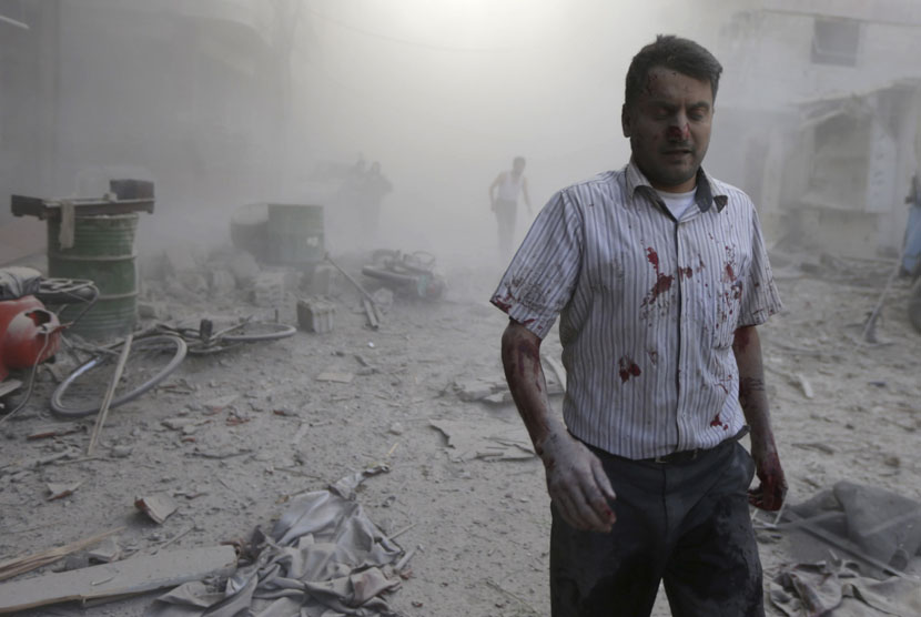   Seorang pria melintasi debu reuntuhan bangunan setelah serangan udara pasukan yang loyal kepada Presiden Bashar al-Assad di Duma, dekat kota Damaskus, Suriah, Kamis (11/9). (Reuters/Bassam Khabieh)