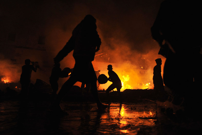 Sejumlah warga berusaha memadamkan api saat terjadi kebakaran pasar Hartaco Makassar, Sulsel, Selasa (16/9) malam.  (Antara/Yusran Uccang)
