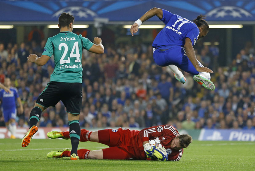  Pemain Chelsea Didier Drogba melompat di atas penjaga gawang Schalke Ralf Faehrmann di Stadion Stamford Bridge, London, Rabu (17/9). (AP/Kirsty Wigglesworth)