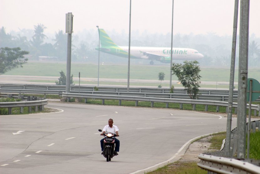  Seorang petugas melintas dengan latar pesawat yang menembus kabut asap saat mendarat di Bandara Internasional Kualanamu Kabupaten Deli Serdang, Sumut, Jumat (19/9).   (Antara/Septianda Perdana)