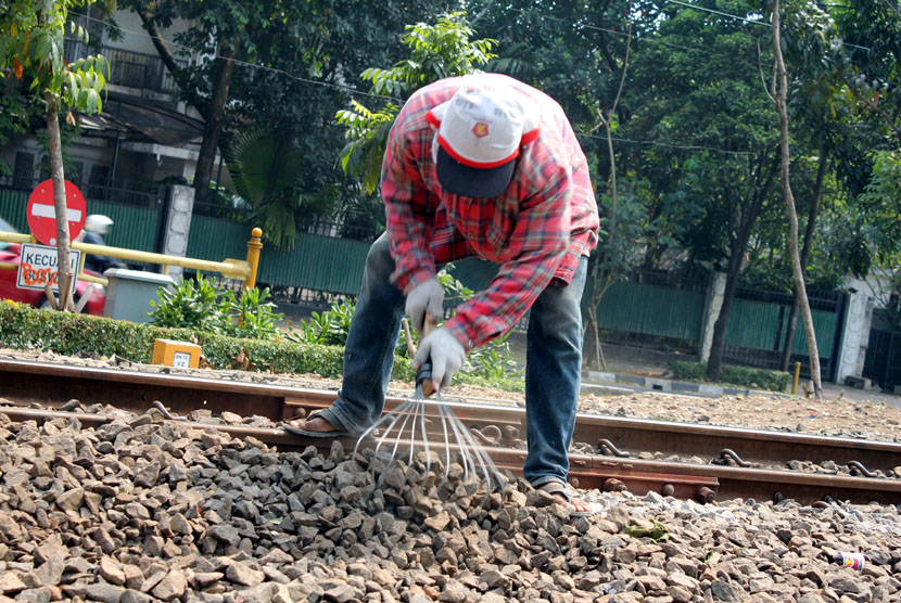   Para pekerja sedang menarik batu untuk penaikan rel kereta api di perlintasan rel kereta api Stasiun Sudirman, Jakarta, Selasa (30/9). (foto : mgROL30)