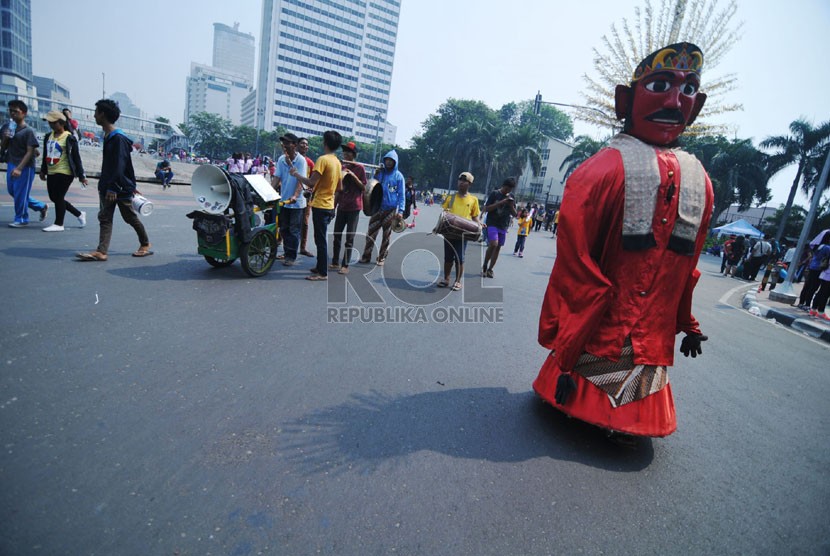   Sejumlah pengamen mengarak ondel-ondelnya untuk mengemis pada saat Car Free Day (CFD) di kawasan Thamrin, Jakarta Pusat, Ahad (12/10). (Republika/Raisan Al Farisi)
