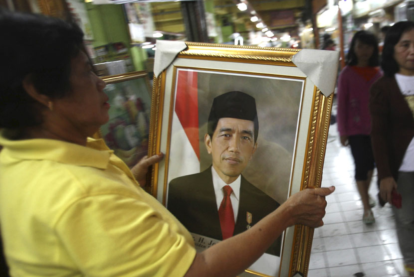 Seorang pedagang memegang foto Joko Widodo di Surabaya. 