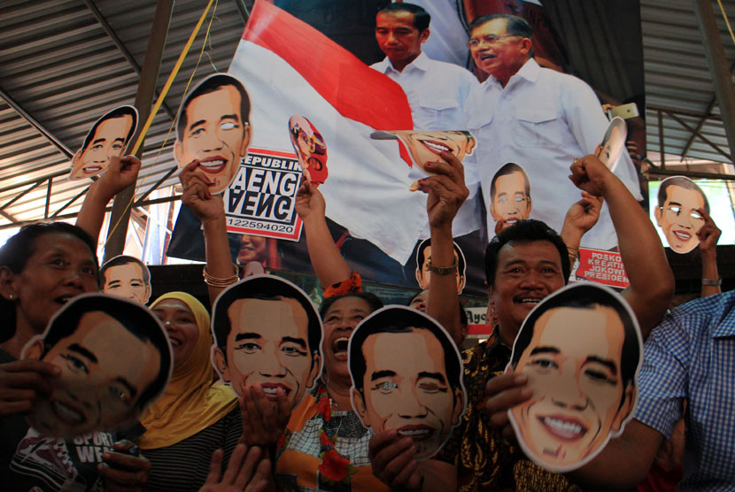   Sejumlah pedagang dan pengunjung mengenakan topeng bergambar Jokowi saat menonton bersama melalui TV acara pelantikan Presiden, Joko Widodo dan wakilnya, Jusuf Kalla di Pasar Gede, Solo, Jawa Tengah, Senin (20/10). (Antara/Maulana Surya)