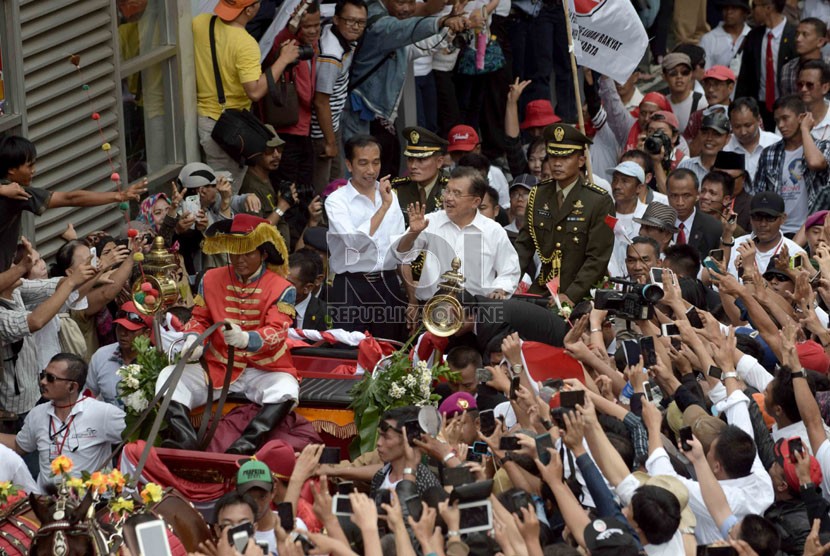  Presiden Joko Widodo dan Wakil Presiden Jusuf Kalla menyapa warga menggunakan kereta kuda menuju Istana, Jakarta, Senin, (20/10). (Republika/Agung Supriyanto)